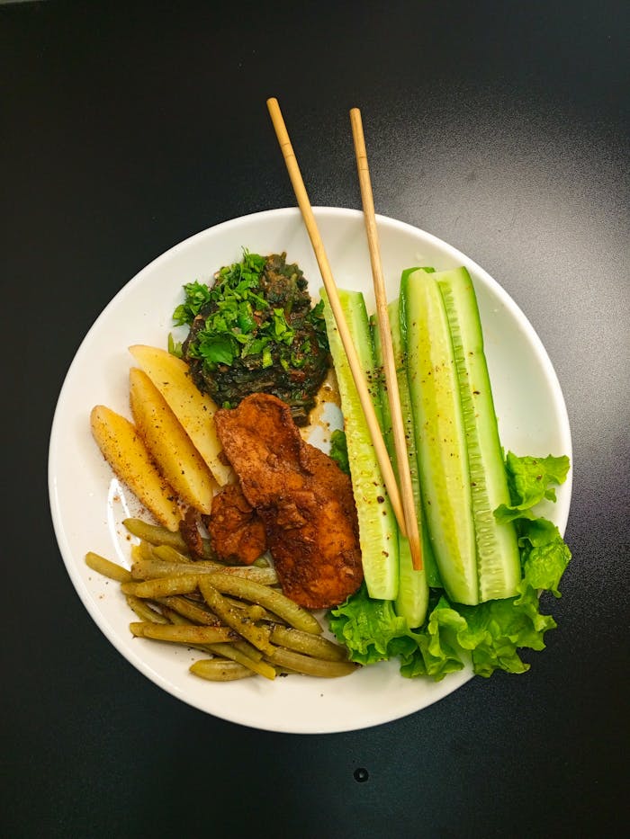 Delicious healthy plate featuring grilled chicken, fresh vegetables, and potato wedges.